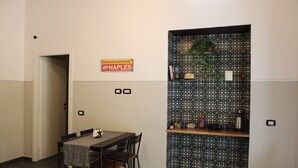 A dining area with a table and chairs, a sign on the wall, and a patterned backsplash. - La Suite del Centro Storico (Naples)