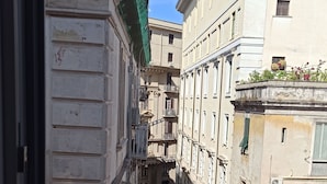 A narrow street with buildings on either side, featuring balconies and a clear blue sky. - La Suite del Centro Storico (Naples)