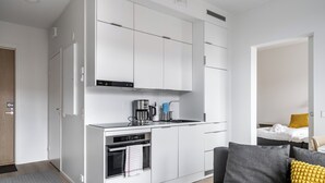 A compact kitchen with white cabinets, a built-in oven, and a coffee maker. - Hiisi Homes Turku Herttuankulma (Turku)