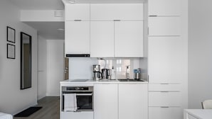 A modern kitchen with white cabinetry, a built-in oven, and a coffee maker. - Hiisi Homes Turku Herttuankulma (Turku)