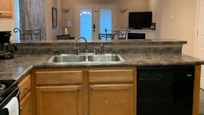 A kitchen with wooden cabinets, a built-in dishwasher, a granite countertop, and pendant lighting. - Lolly Gris-Gris (Hot Springs)