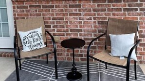A cozy seating area with two chairs and a small table, a brick fireplace, and a wall-mounted lantern. - Lolly Gris-Gris (Hot Springs)