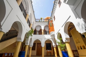 Une cour intérieure avec des arcades, une porte en bois et des plantes en pot.