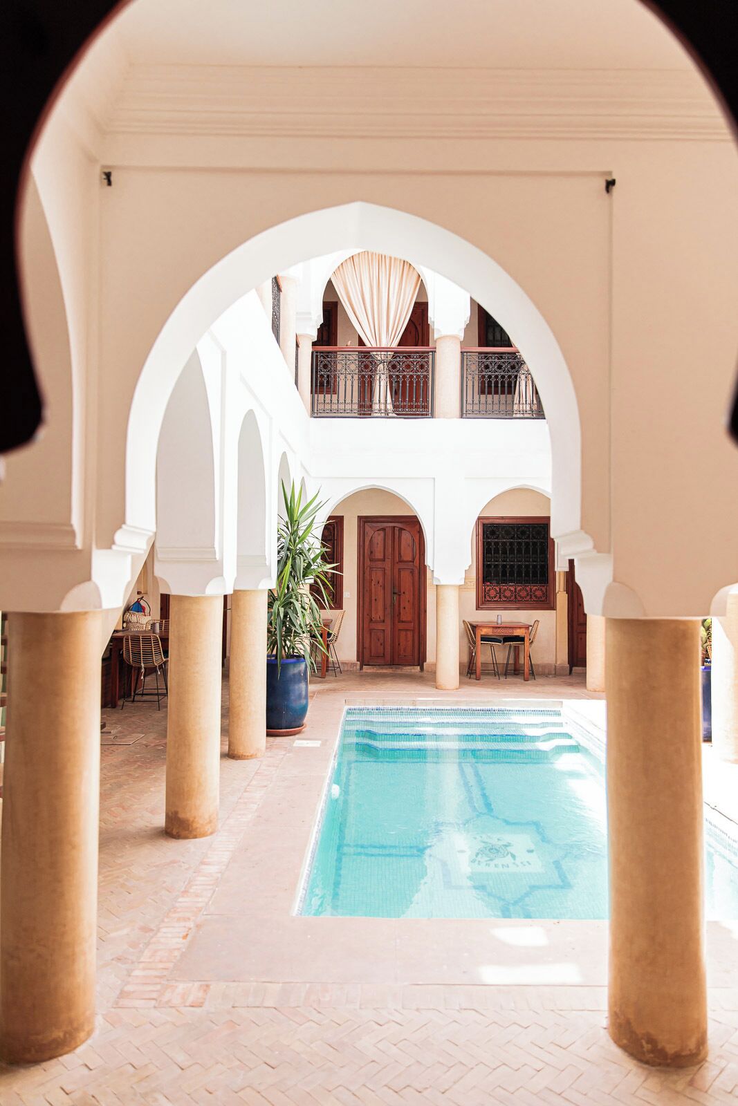 A pool area with a two-story building, columns, and a door.