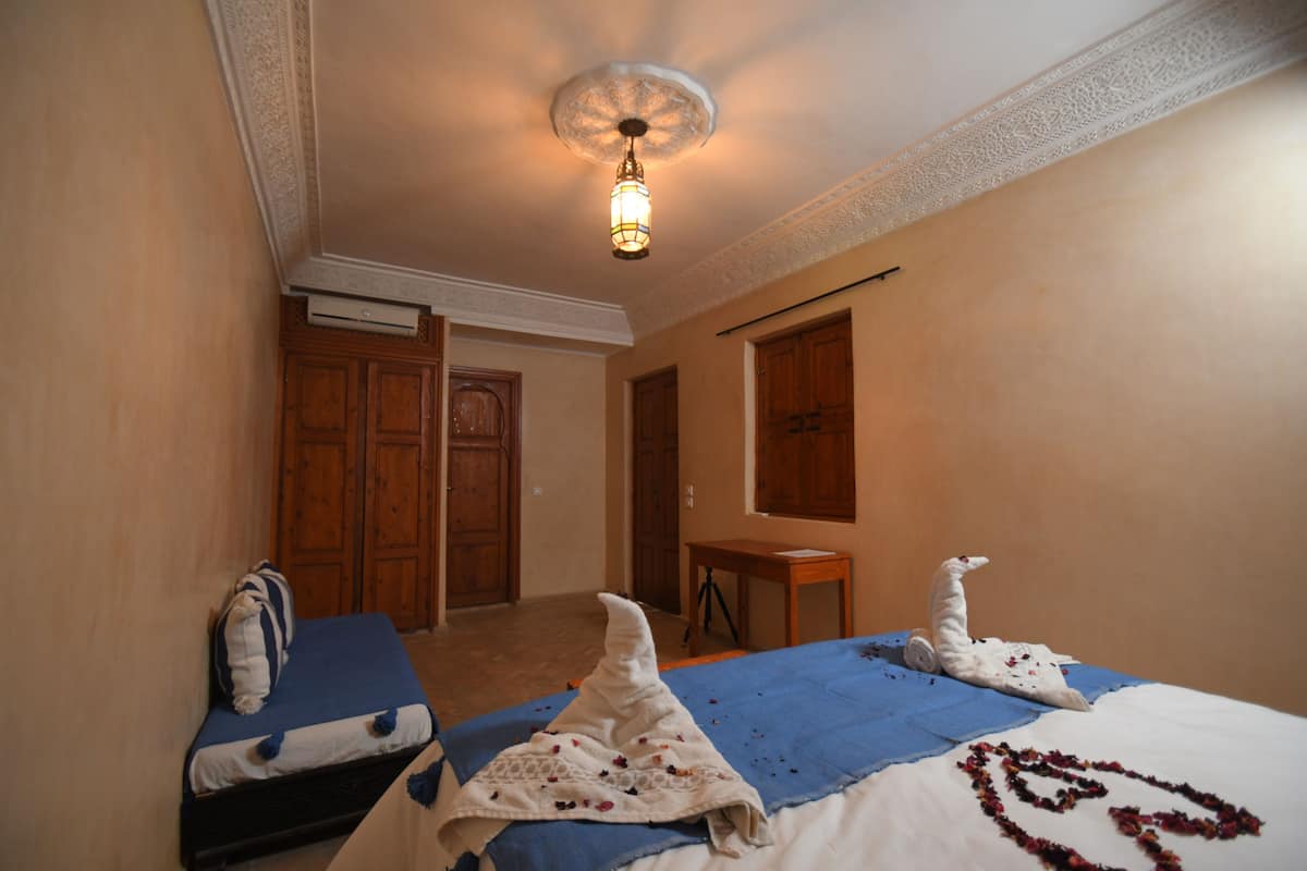 Et hotelværelse med to senge, et skrivebord og et skab.