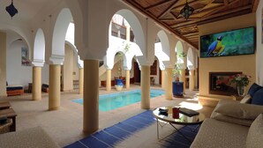 Zona interior àmplia amb una piscina, seients còmodes i una televisió.