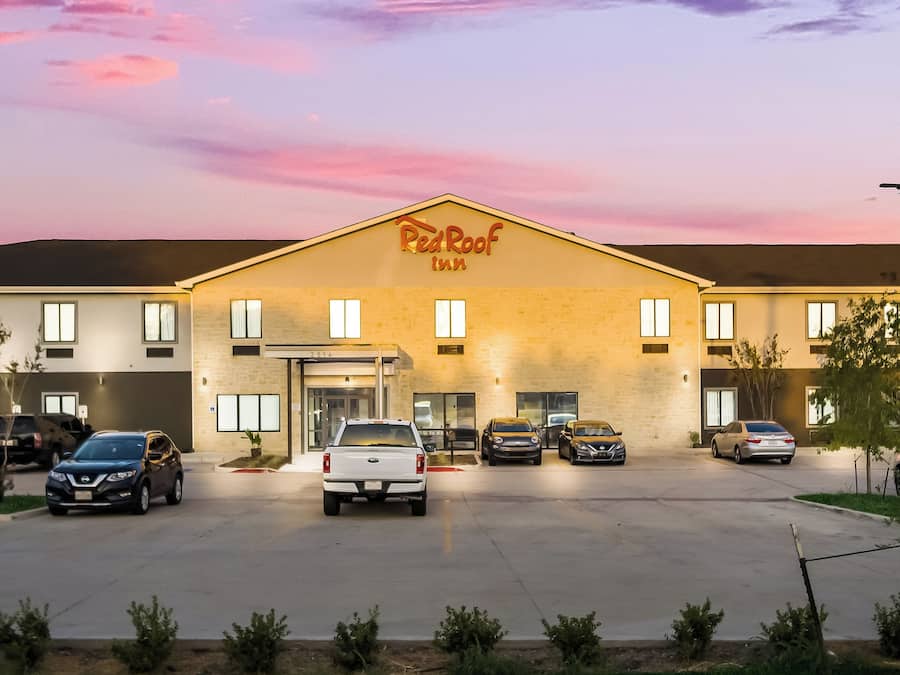 Un hôtel Red Roof Inn avec un parking, plusieurs voitures et un ciel dégagé.