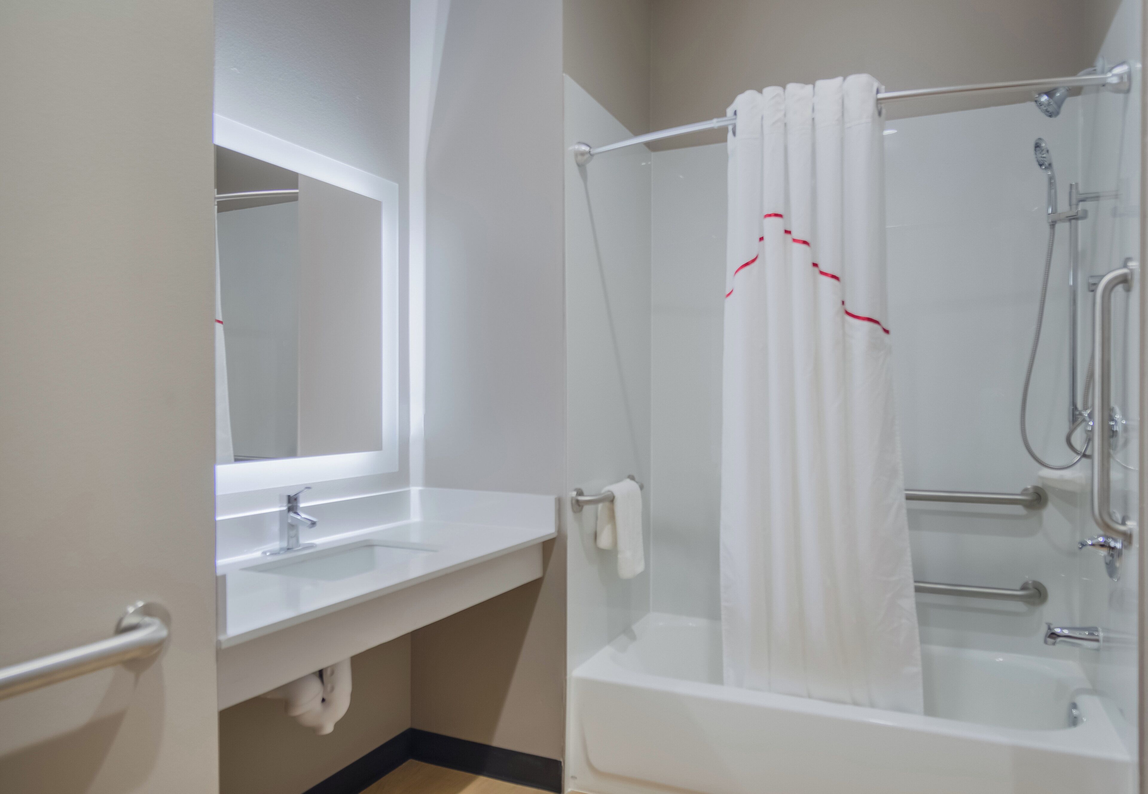 A bathroom with a white sink, a mirror, a shower with a white curtain, and a bathtub.