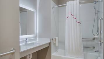 A bathroom with a white sink, a mirror, a shower with a white curtain, and a bathtub.