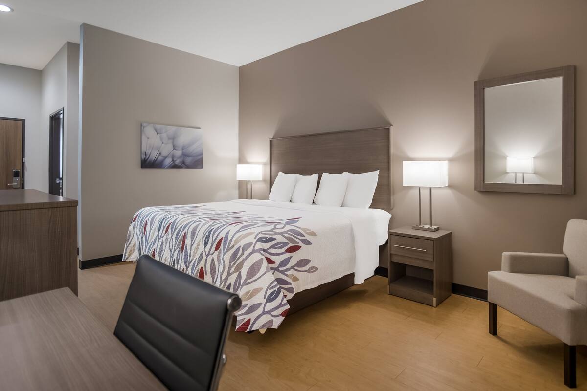 Ett hotellrum med en säng, sängbord, ett skrivbord, en stol och en stor spegel.