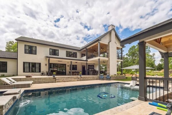 A modern two-story house with a swimming pool, outdoor seating area, and a covered patio.