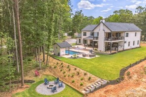 A large, two-story house with a spacious backyard, including a swimming pool and outdoor seating area.