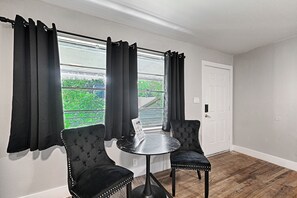 Una habitación con dos sillones tapizados, una mesita redonda y un ventanal con cortinas.