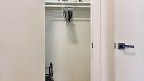 Un couloir menant à un placard équipé d’étagères et de barres pour suspendre des vêtements.
