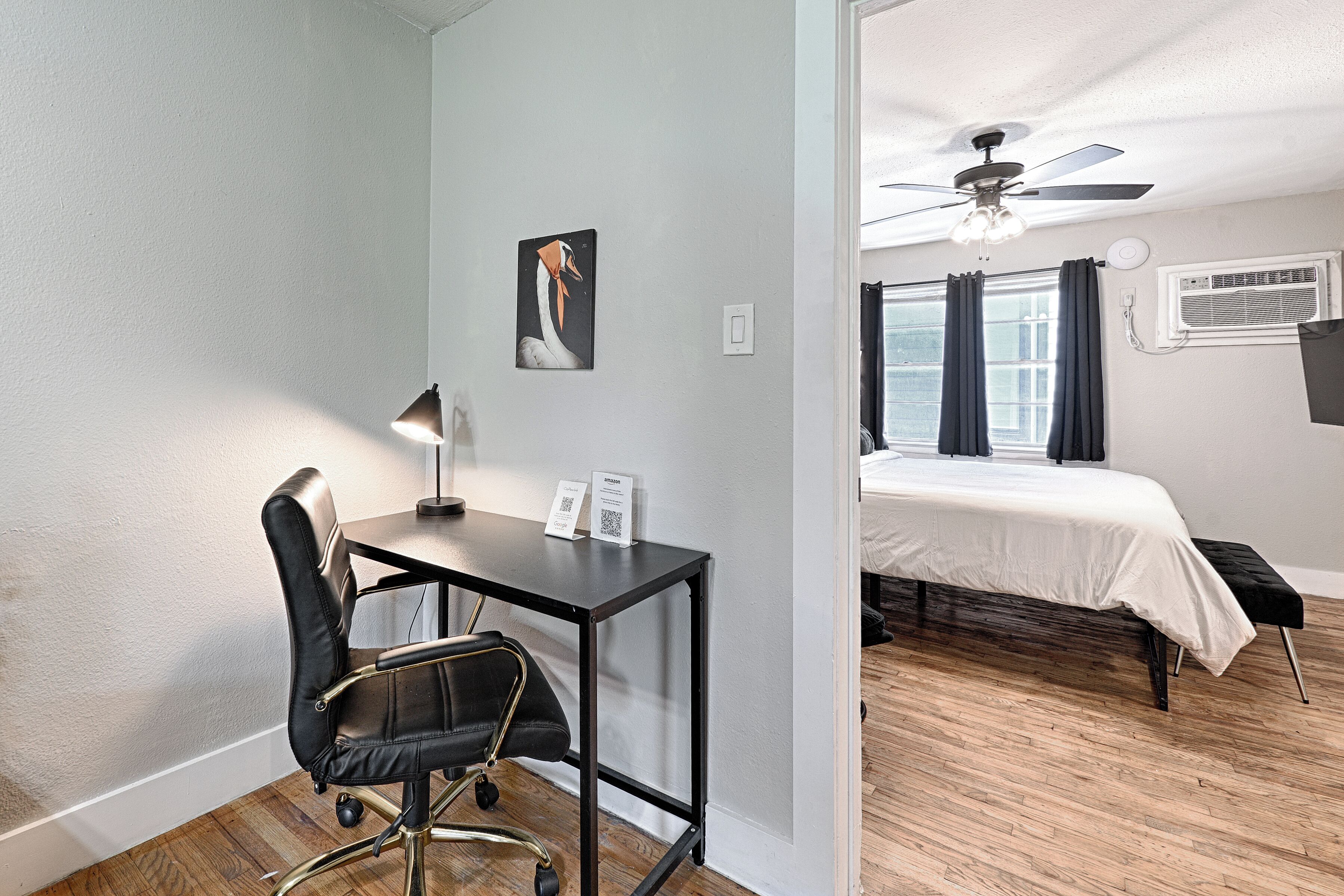 A room with a desk, chair, bed, and a ceiling fan.