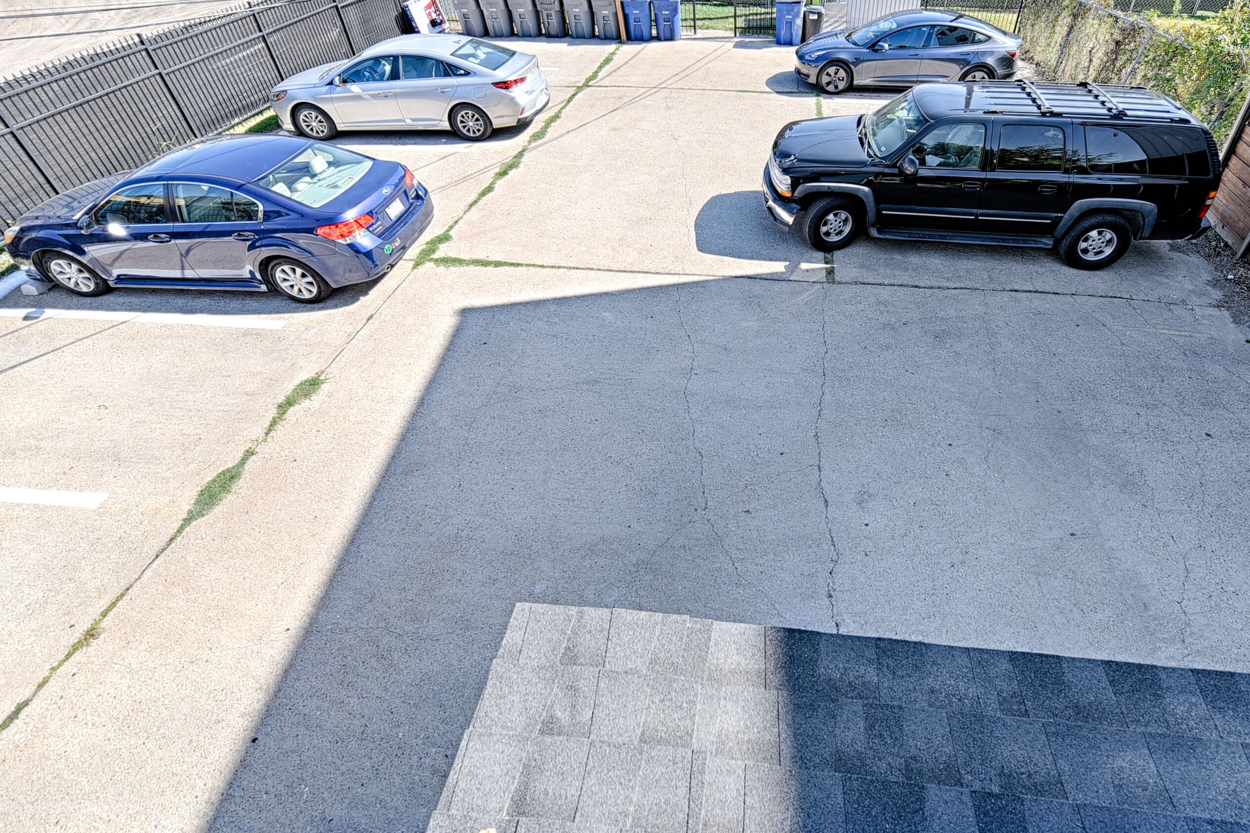 A parking lot with several cars, including a blue sedan and a black SUV.