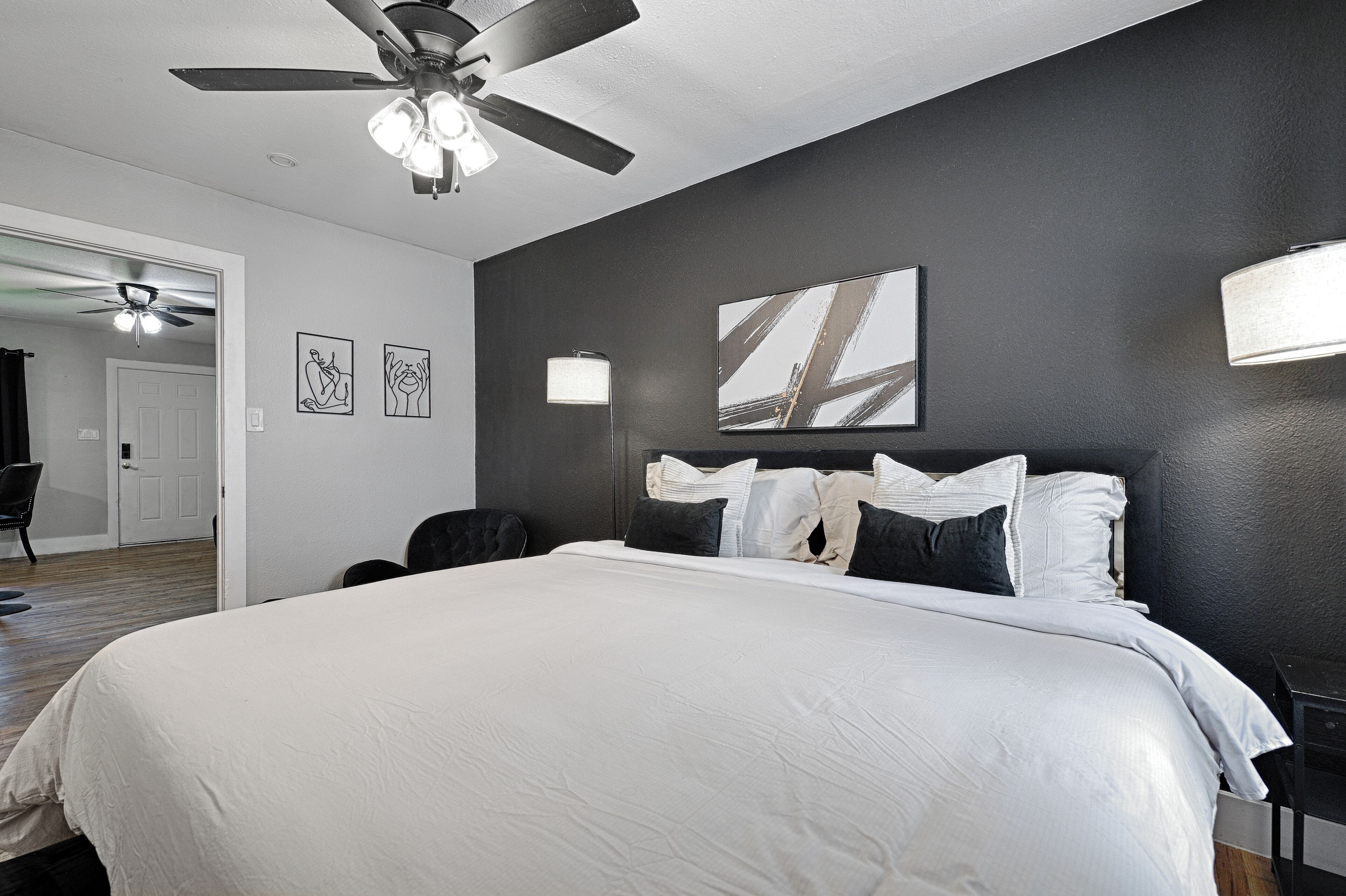 Une chambre d’hôtel avec un grand lit, un ventilateur de plafond et des œuvres d’art accrochées aux murs.