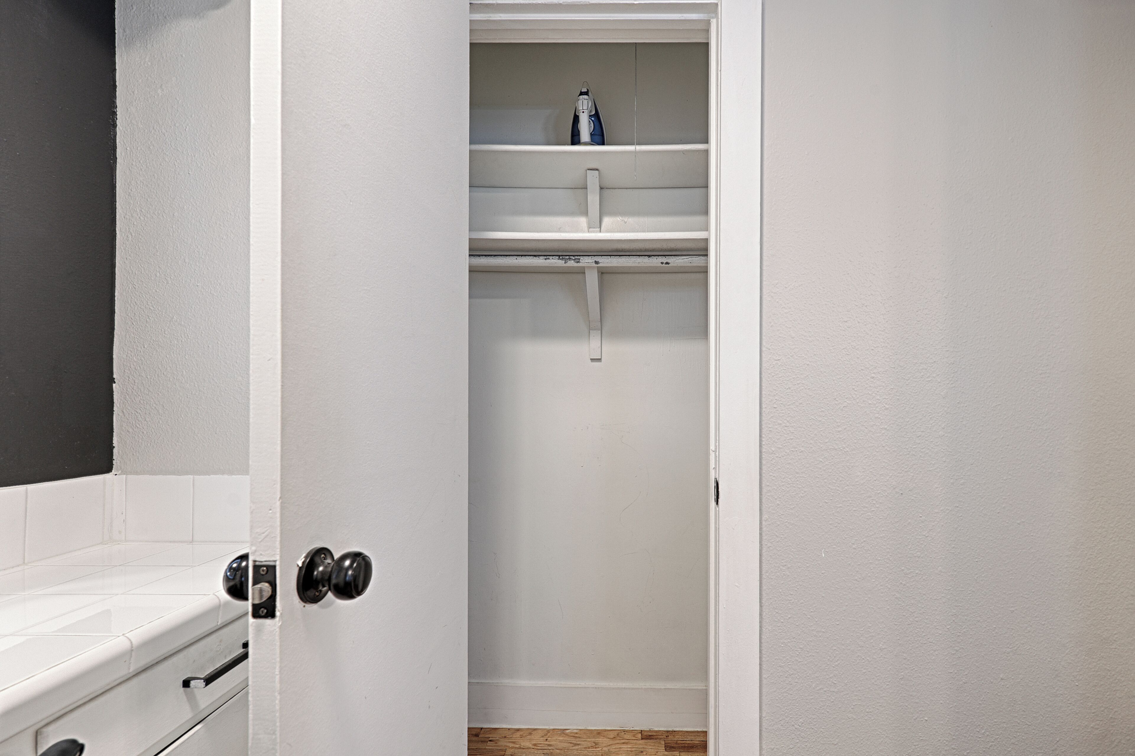 A bathroom with a white bathtub, a shower, and a shelf with a bottle.