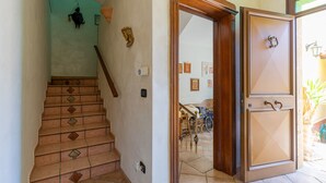 Eine Treppe mit gemusterten Fliesen, eine Holztür mit Griff und eine wandmontierte Leuchte.
