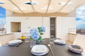 A rooftop terrace with a dining table set for four, a potted plant, and a view of the cityscape. - LecasinediCo` - Alessandra by BarbarHouse (Castrignano del Capo)