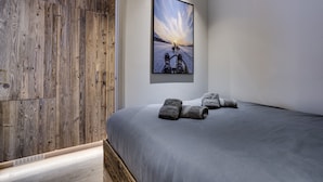 Quarto com uma cama grande, um guarda-roupa de madeira e um quadro emoldurado de uma paisagem nevada.