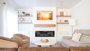 A modern living room with a fireplace, leather sofas, and artwork on the walls. - Rustic Gold Retreat (Kanab)
