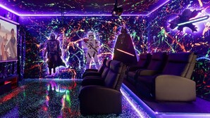 A room with a movie screen, reclining chairs, and a vibrant, colorful wall with abstract designs.