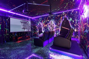 A room with a large screen, seating, and a ceiling projector.