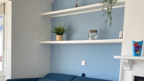 A living room with a blue sofa, white shelves, and a fireplace.