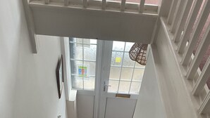 A staircase with a handrail, a doormat, and a door with a window.