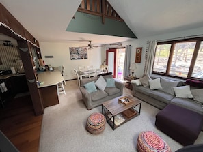 A living room with a sofa, ottoman, coffee table, and a dining area with chairs and a table.