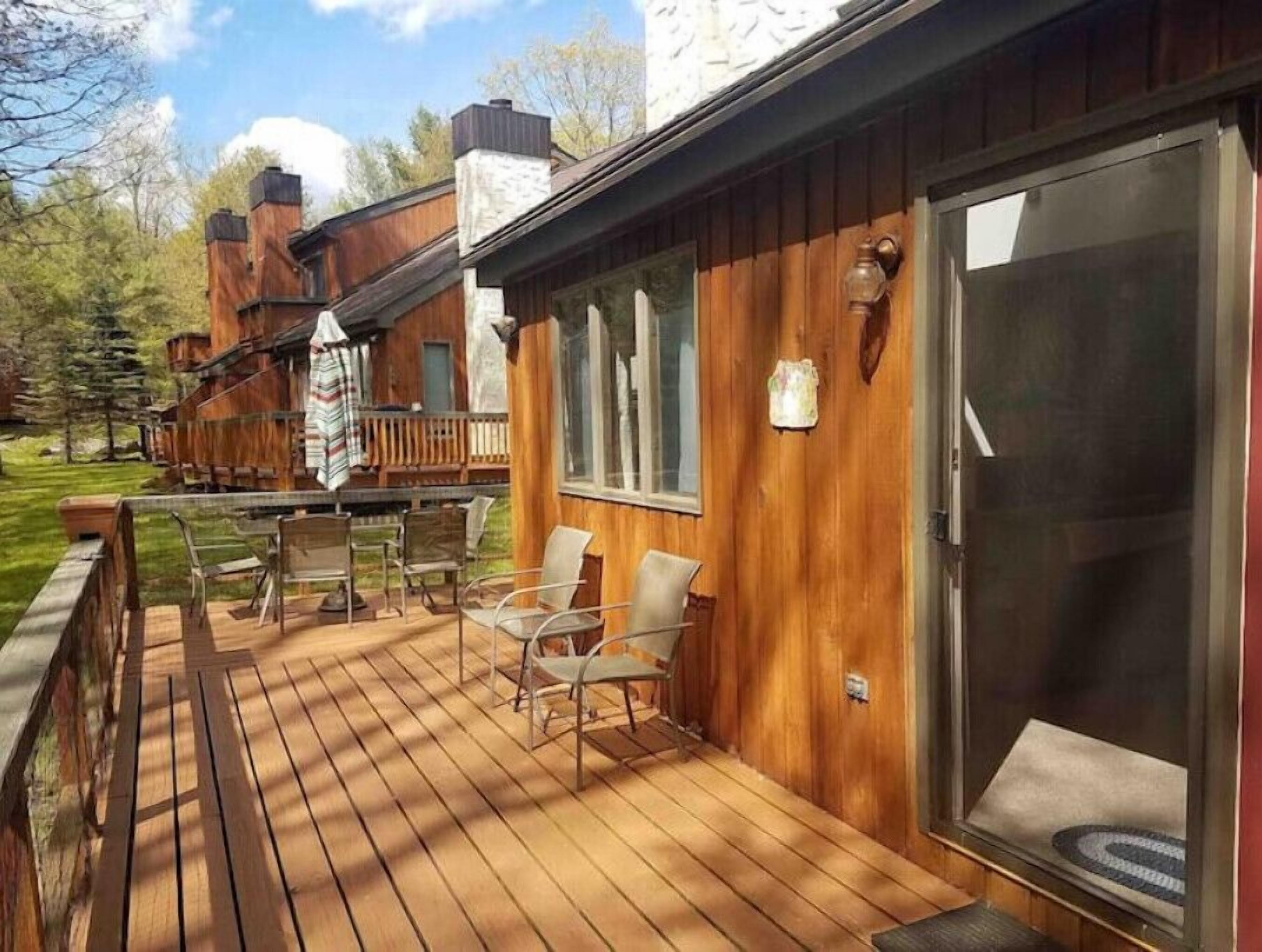 Eine Holzterrasse mit Sitzgelegenheiten und einer Schiebeglastür.
