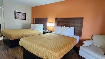 A hotel room with two beds, a nightstand, a chair, and a wall-mounted lamp.