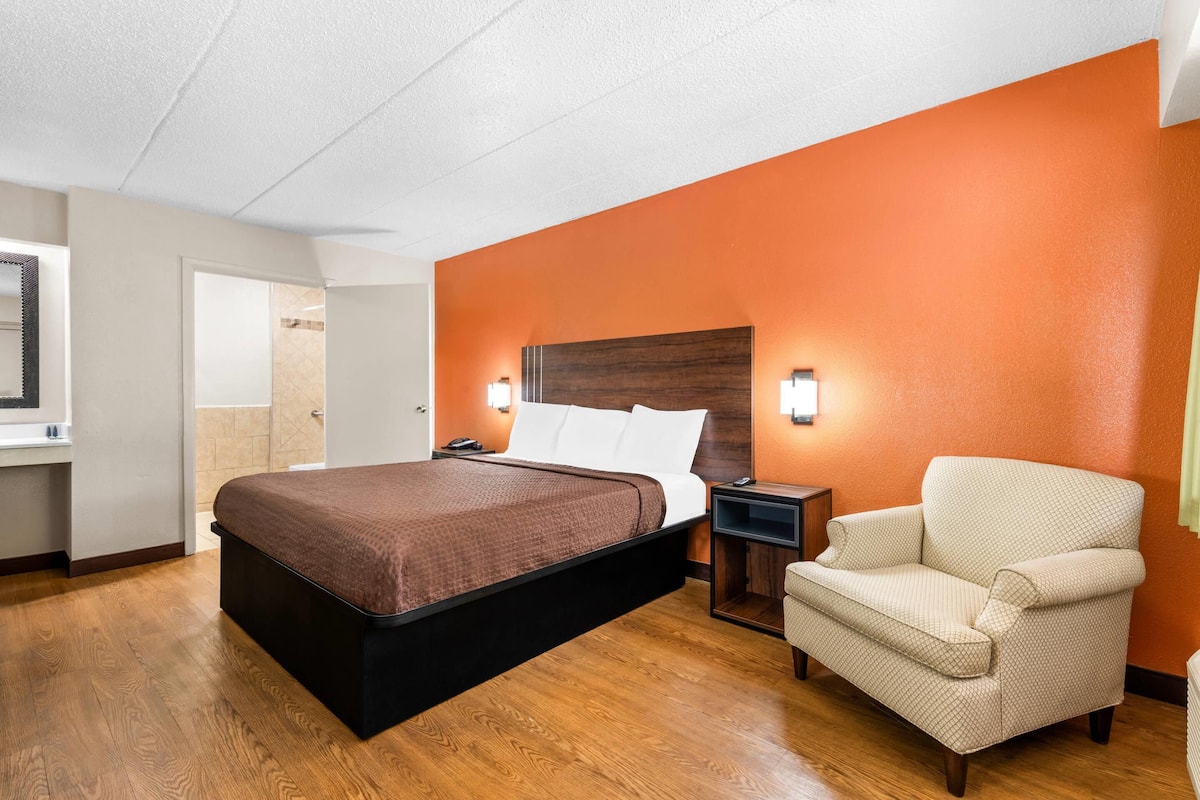 Une chambre d’hôtel avec un grand lit, une table de chevet, une chaise et un plancher en bois.