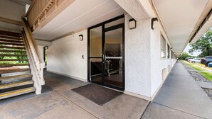 Une entrée abritée avec un escalier en bois menant à une porte en verre.