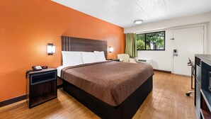 Une chambre d’hôtel avec un grand lit, une table de chevet, un bureau et une vue sur l’extérieur.