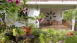 A garden with potted plants and flowers in front of a building with a balcony.