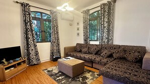 A living room with a sofa, ottoman, and a TV stand.
