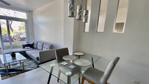 A modern living room with a glass dining table, grey sofa, and abstract wall art. - Rooftop with ocean view, minigolf & pool and 1 queen bed (Guanacaste)