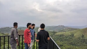 Un grupo de personas en un balcón con vistas a un paisaje montañoso.