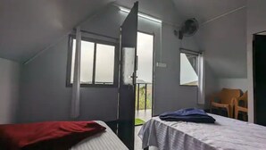 Una habitación con una cama, una silla y un ventanal.