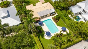 An aerial view of a residential area with a swimming pool surrounded by palm trees and a well-maintained lawn. - Best Location in Olde, South Naples! (Naples)
