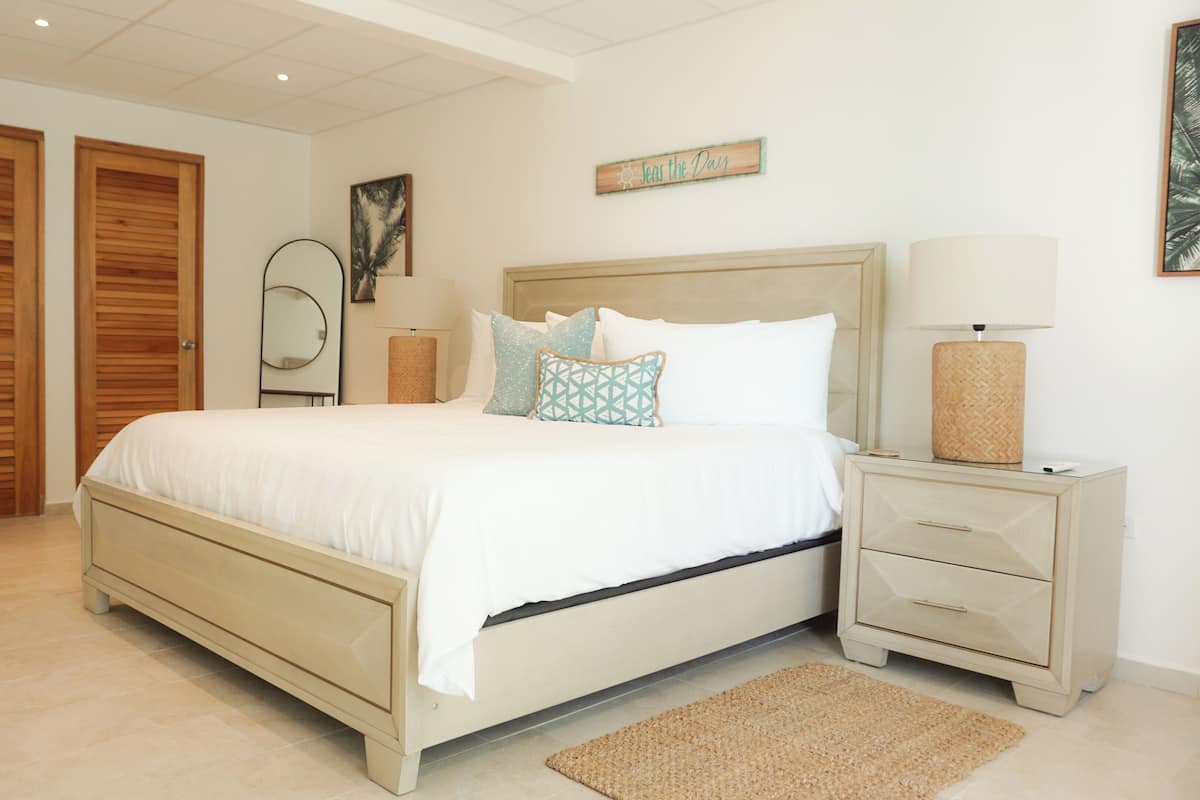 A bedroom with a bed, bedside tables, a mirror, and a wall-mounted sign.