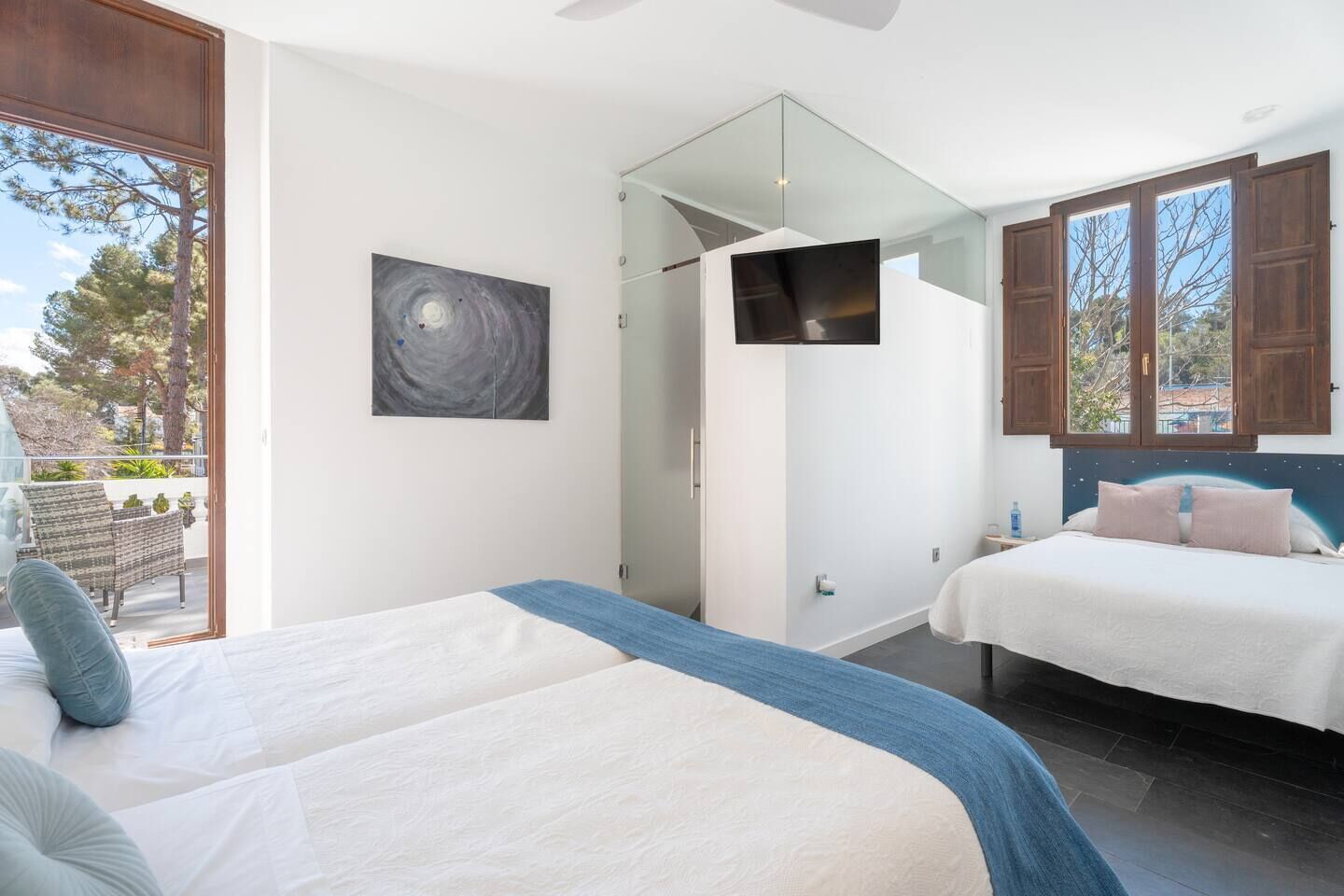 Une chambre moderne avec deux lits, une grande fenêtre, un tableau et un téléviseur.