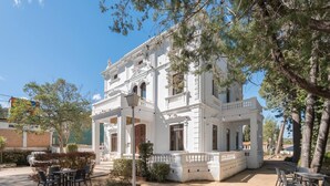 Un bâtiment blanc doté d’un balcon, d’une terrasse et entouré d’arbres.