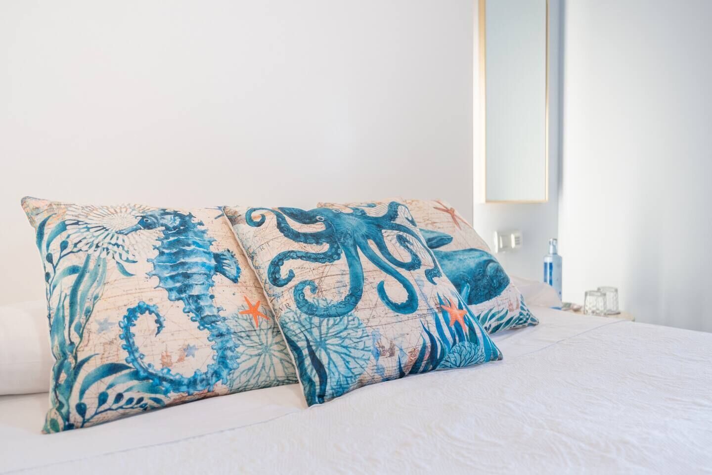 A bed with two decorative pillows featuring oceanic designs.