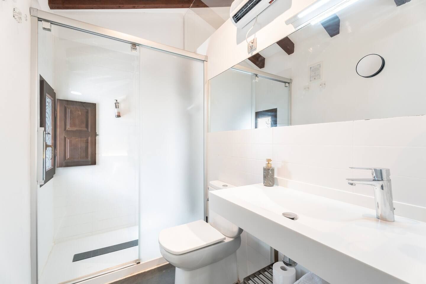 Uma casa de banho moderna com cabine de duche em vidro, lavatório branco e sanita.