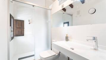 Uma casa de banho moderna com cabine de duche em vidro, lavatório branco e sanita.