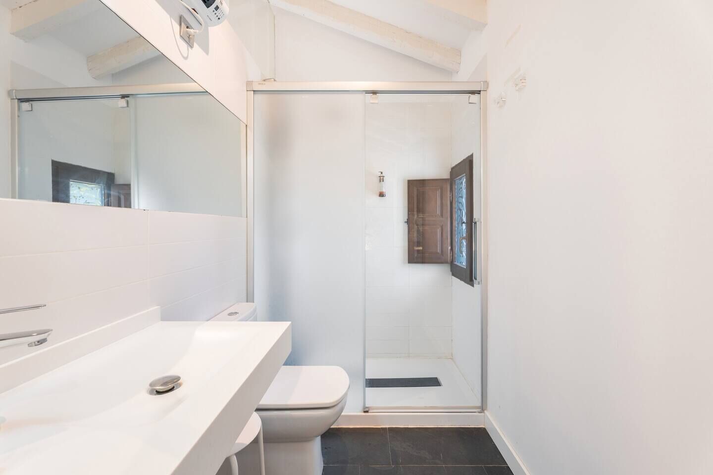 Une salle de bain moderne avec une douche à parois de verre, un lavabo blanc et des toilettes.