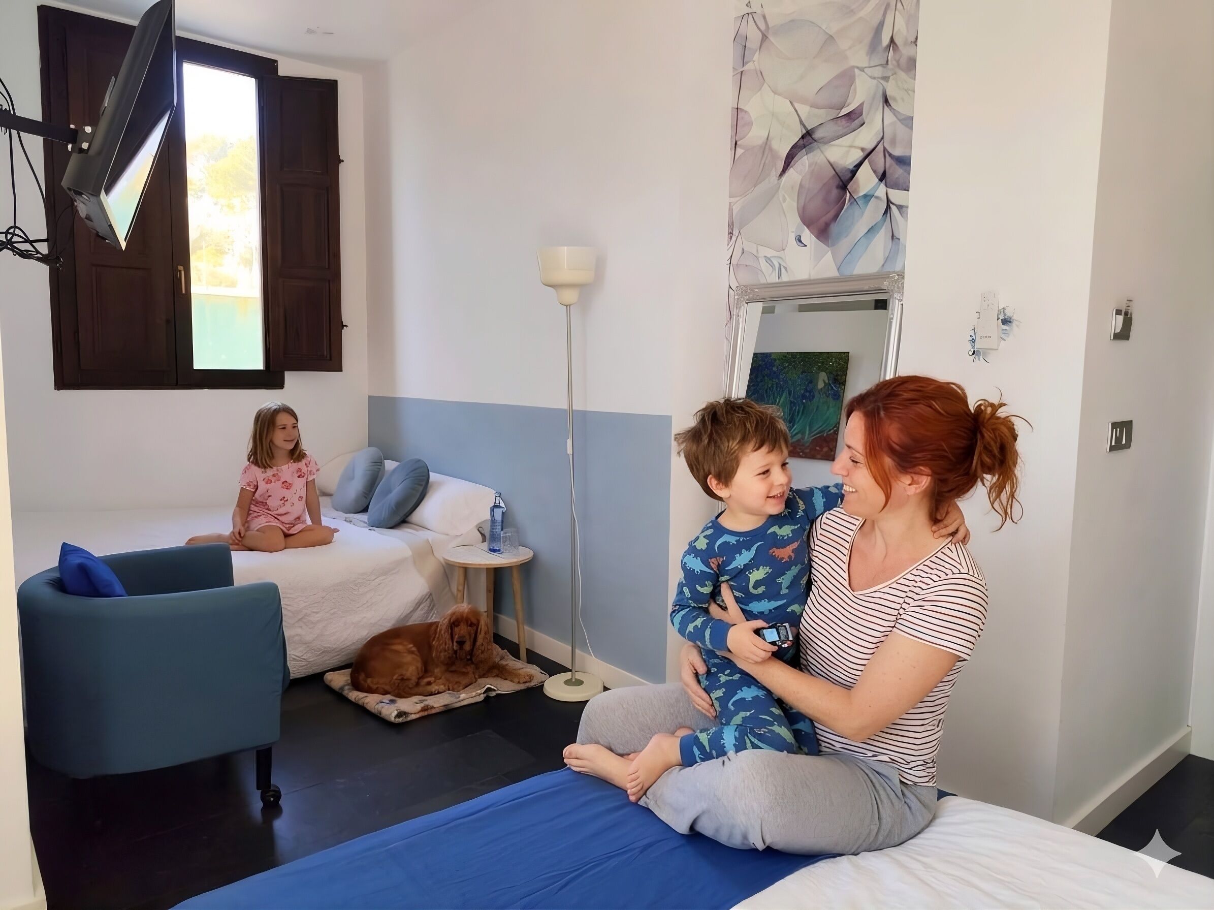 Una habitación con una cama, un sofá azul, una lámpara de pie y una cama para perro.